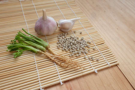 Garlic, pepper, coriander root, On wooden mat, Spices for cookingの写真素材