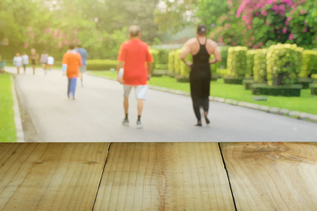 Wooden foreground with blurred public parks, People are jogging, Health and nature conceptの写真素材