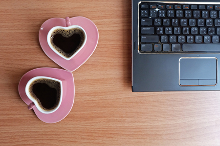 Black coffee in  two cups heart shape and laptop computer on wooden floor, Top view, copy spaceの写真素材