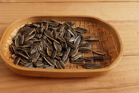 Sunflower seeds in bamboo basket on wooden backgroundの写真素材
