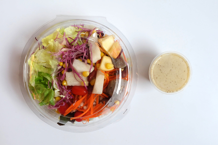 Fresh Salad and dressing with Black sesame In clear plastic box on white backgroundの写真素材
