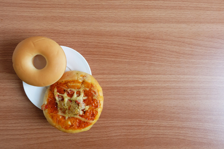 Snacks with Donut bread and Pizza in a white plate on wooden table Topview.の写真素材
