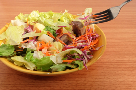 Salad and Caesar dressing with Black sesame on fork and salad on plate on wooden floorの写真素材