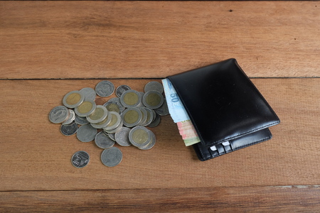 Black leather wallet with money Banknotes and coins on wooden floor