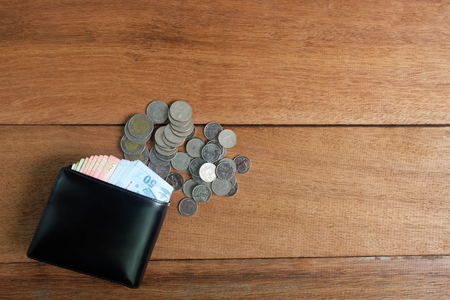 Black leather wallet with money Banknotes and coins on wooden floorの写真素材