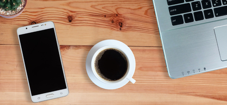 Black coffee in white cup and laptop computer and Mobile Phone or Smartphone with blank screen on wooden floor, Horizontal photo banner for website header design Top view, copy spaceの写真素材