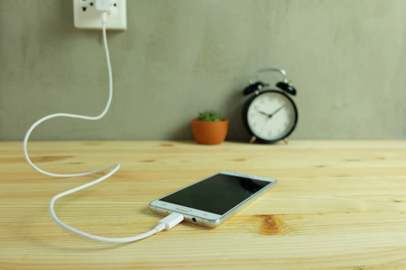 Plug in power outlet Adapter cord charger of mobile phone on wooden floorの写真素材