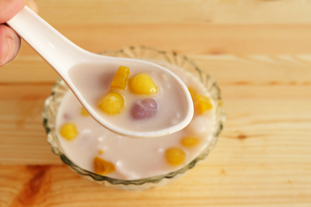 Colorful thai dessert "bua loy or bua Loi" Contains coconut milk, glutinous rice powder with poached egg, on wooden floorの写真素材