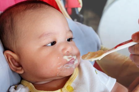 The cute Asian baby boy newborn eating glutton by mother feeding food supplements for babiesの写真素材