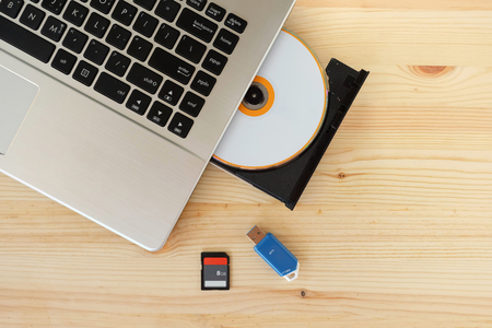 SD Card, Flash Drive USB3.0 and CD DVD Drive Writer Burner Reader of laptop computer on wooden background, Concept of Data storage deviceの写真素材