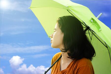 Cute asian woman holding umbrella with sunlight and blue sky and Cloud background in the hot weather In summerの写真素材