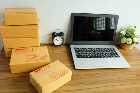 Laptop computer and Product Box or shipping parcel box on a wooden table, Online shopping, work at home, e commerce.の写真素材