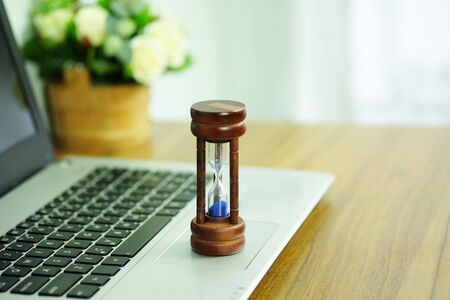 Wooden hourglass on a laptop computer, Managing time and countdown to deadline concept