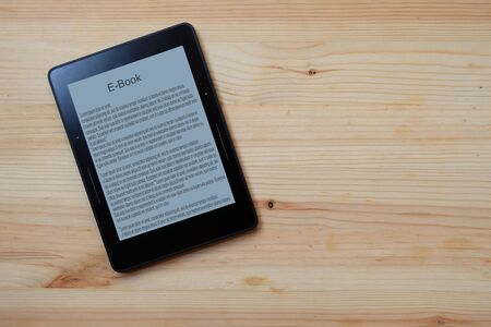 E-book reader on wooden table background, Top view