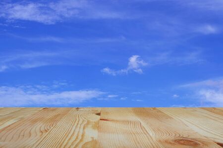 Old wooden table and empty front and blue sky background, Empty space place a product,  texture with natural wood pattern for design.の写真素材