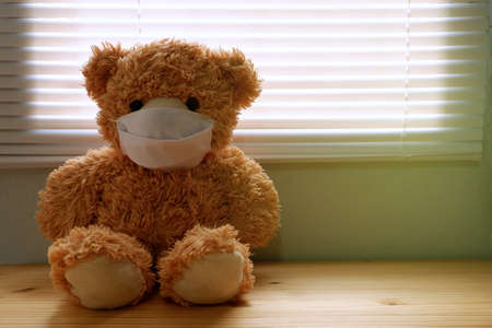 Teddy bear wearing a face mask, by the window with loneliness and Sadness. Coronavirus Covid-19 and pm2.5, stay at home, quarantine concept.の写真素材