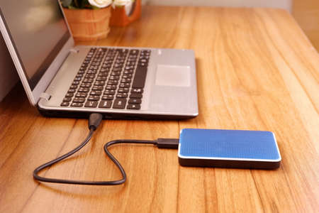 Portable external hard drive USB3.0 connect to laptop computer on desk, Data transfer or backup personal files conceptの写真素材