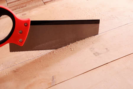 A hand saw is cutting sheet wood.の写真素材