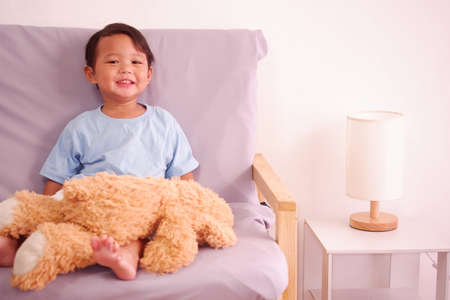 Cute asian boy about 2 years old smiling on the sofa in the living room.の写真素材