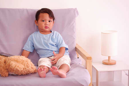 Cute asian boy about 2 years old smiling on the sofa in the living room.の写真素材