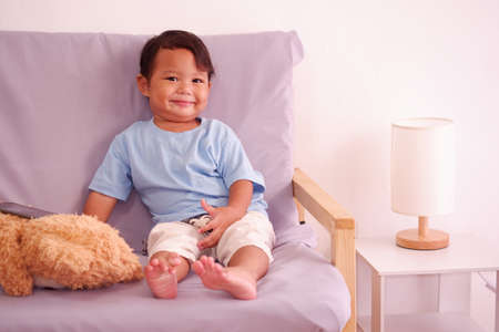 Cute asian boy about 2 years old smiling on the sofa in the living room.の写真素材
