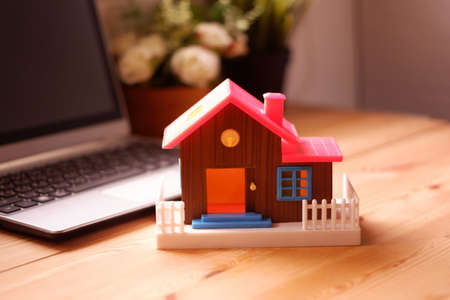 Toy house on desk with laptop computer, The concept of buying a dream home for beginners workingの写真素材