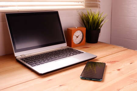 Laptop computer and smartphone on wooden desk by the windowの写真素材