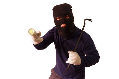 Masked thief holds steel crowbar in preparation for a pry and shines his torch turned to look with a doubtful expression Isolated on white backgroundの写真素材