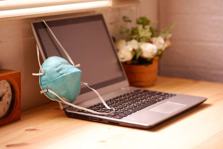 Work from home or quarantine with Surgical mask or hygienic mask and laptop computer on wooden desk, Protection factors for covid-19, corona virus, pm2.5の写真素材