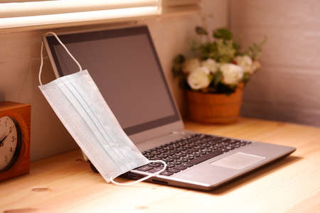 Work from home or quarantine with Surgical mask or hygienic mask and laptop computer on wooden desk, Protection factors for covid-19, corona virus, pm2.5の写真素材