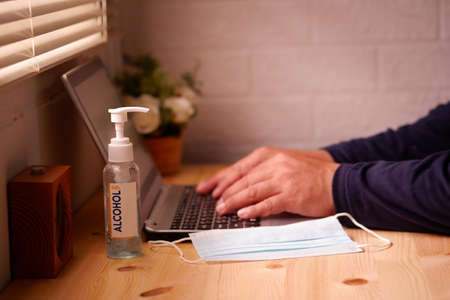 Business men working from home with Surgical mask or hygienic mask on laptop computer with Sanitizer alcohol gel for hand. Protection factors for covid-19, corona virus, pm2.5の写真素材