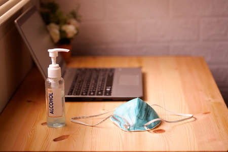 Work from home or quarantine with Surgical mask or hygienic mask and Sanitizer alcohol gel for hand with laptop computer on wooden desk, Protection factors for covid-19, corona virus, pm2.5の写真素材