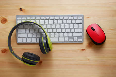 White keyboard with wireless mouse and   wireless headphones on woodenの写真素材