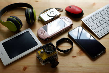 Smartphone with portable game consoles and ebook reader and other electronic gadgets on wooden background.Top view.の写真素材