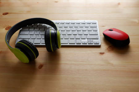 White keyboard with wireless mouse and wireless headphones on woodenの写真素材