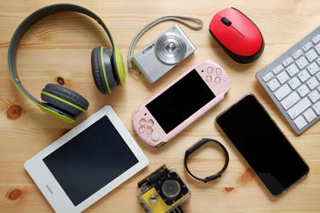 Smartphone with portable game consoles and ebook reader and other electronic gadgets on wooden background.Top view.の写真素材