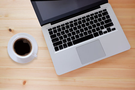 Laptop computer and black coffee in white cup on wooden desk with copy space, Top view.の写真素材