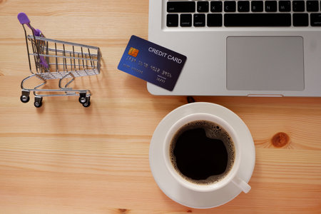Shopping cart and credit card and laptop computer with black coffee in white cup. Concepts of online shopping or delivery where consumers can buy products directly from home or work.の写真素材