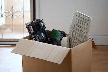 Old hard disk dive and motherboards and used keyboard with mouse old computer hardware accessories in paper boxes, Obsolete equipment is electronic waste Reuse and Recycle concept.の写真素材