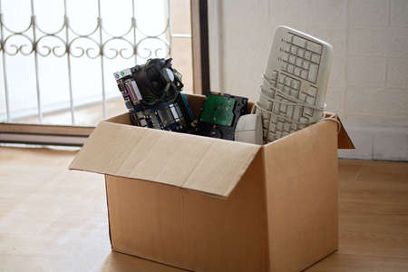 Old hard disk dive and motherboards and used keyboard with mouse old computer hardware accessories in paper boxesの写真素材