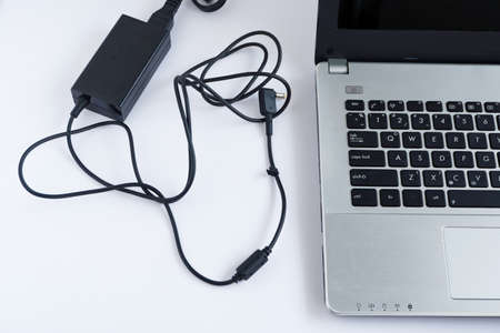 Messy charging cable adapter of laptop computer on white backgroundの写真素材