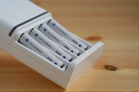 Selective focus rechargeable AAA battery in a white charger on wooden background.の写真素材
