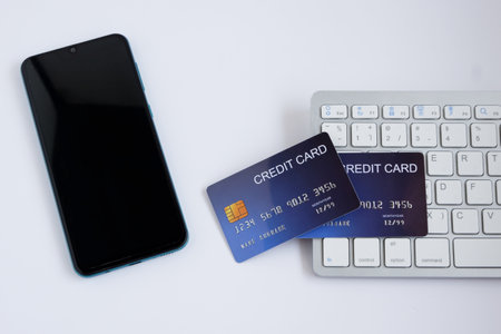 Credit card on computer keyboard with smartphone on white desk. Concept of Online shopping and payment. Top view.の写真素材