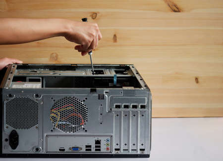 Hands of a mechanic with a screwdriver repairing and assembling desktop computer internal partsの写真素材