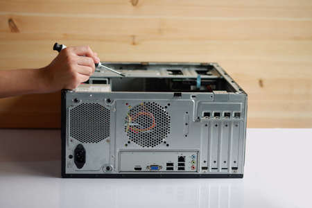 Hands of a mechanic with a screwdriver repairing and assembling desktop computer internal partsの写真素材