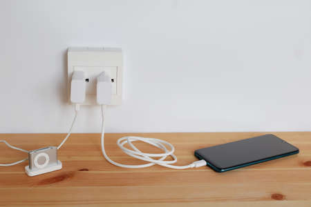 Plug in power outlet Adapter cord charger of smart phone and mp3 players, gadgets, on wooden floorの写真素材