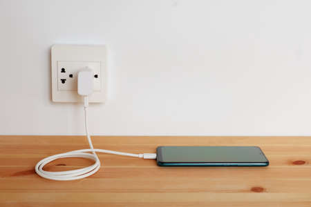 Plug in power outlet Adapter cord charger of smart phone on wooden floorの写真素材