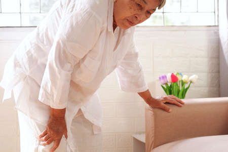 Elderly Asian woman with grey hair holding a leg that is painful from varicose veins or from osteoarthritis, Various illnesses of the elderly and good health concept.の写真素材
