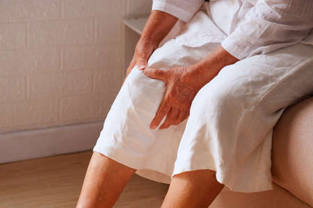 Elderly Asian woman holding a leg that is painful from varicose veins or from osteoarthritis, Various illnesses of the elderly and good health concept.の写真素材