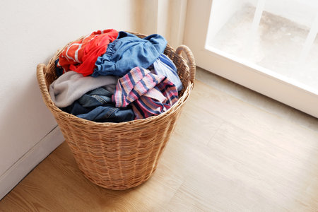 Wooden wicker basket that holds lots of used clothes and prepares them for washing.の写真素材